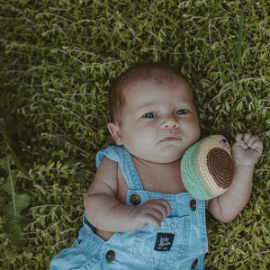 Baby in grass holding Crochet Handmade Avocado Toy Rattle