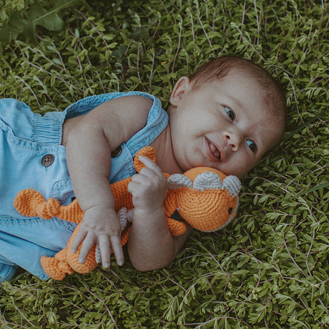 Baby holding Orange Crochet Dino Toy