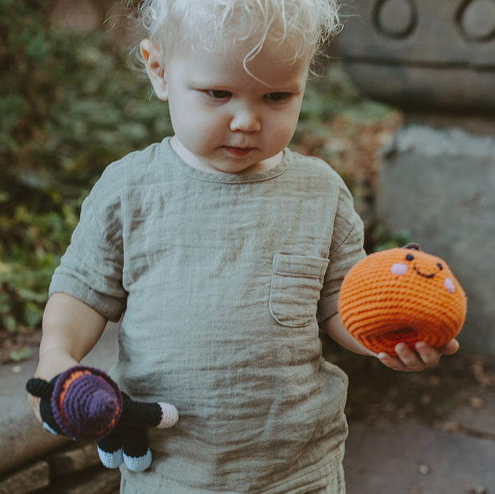 Todler with Orange Pumpkin Plush Toy and Black Cat