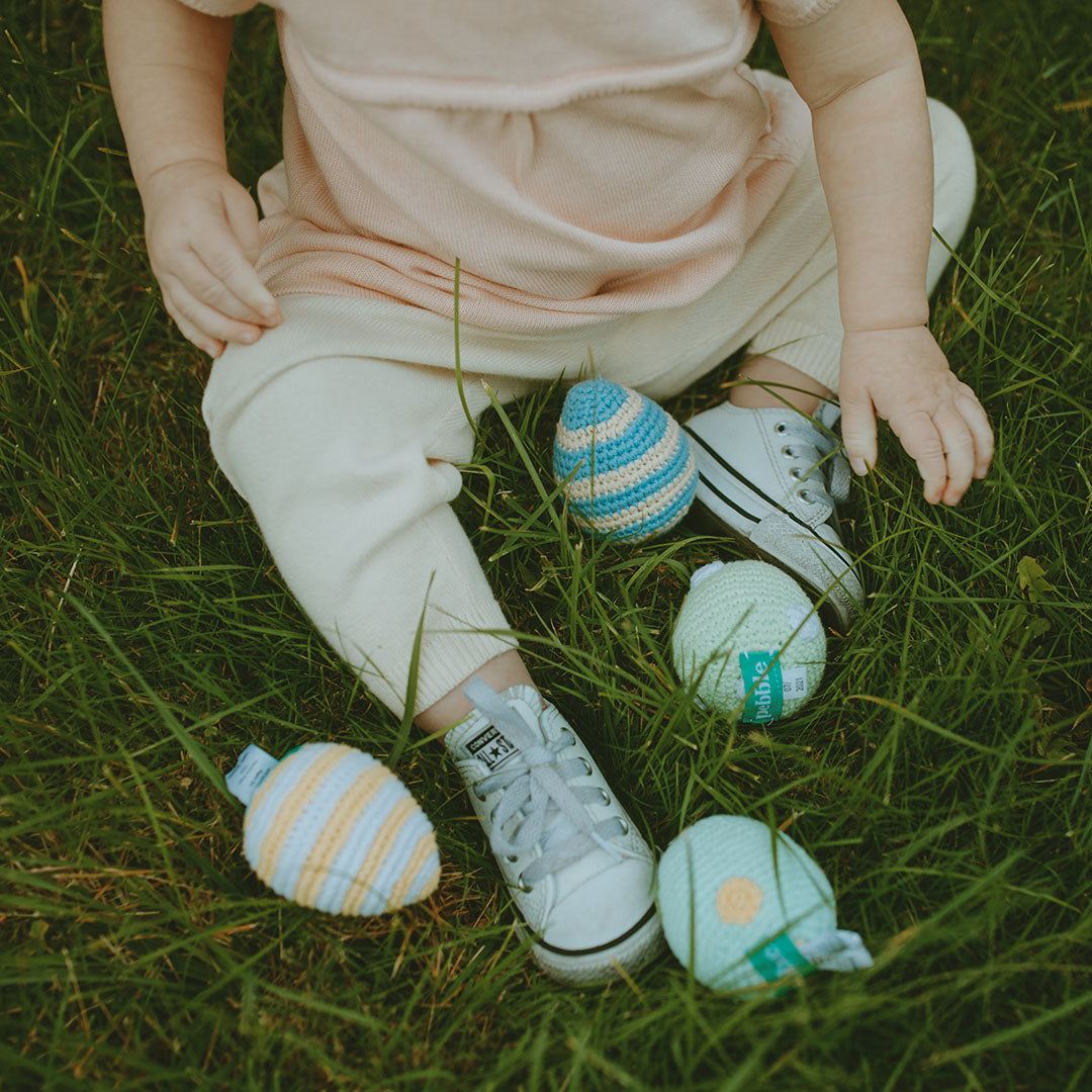 Toddler with Crochet Easter Egg Plush Toys in Grass