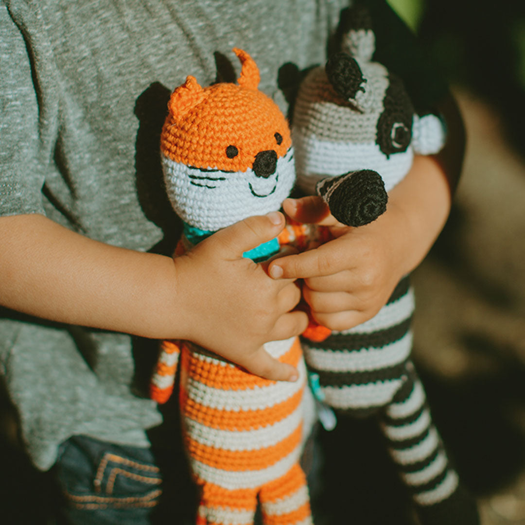 Toddler hugging Handmade Fox and Raccoon Plush Toys