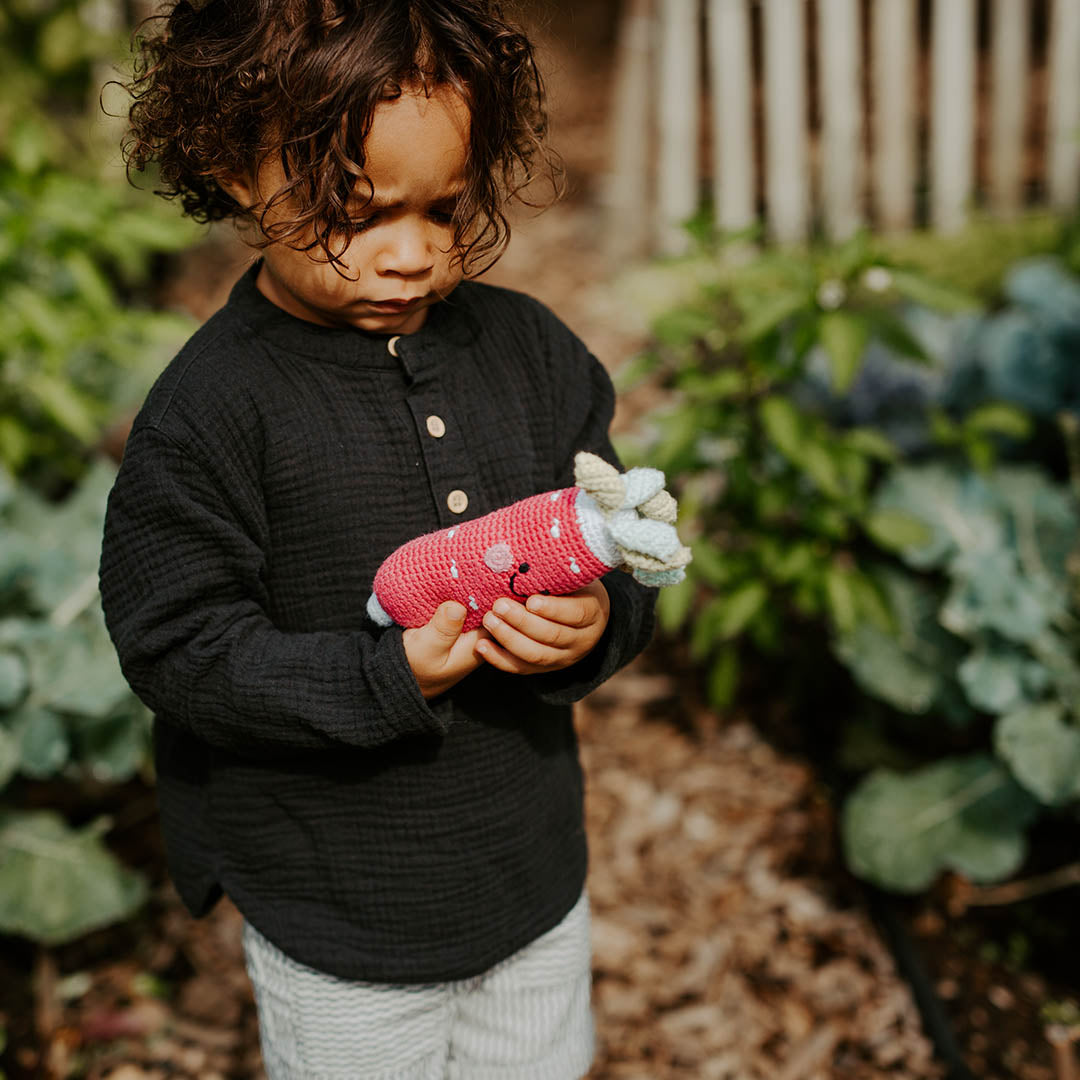 Child in garden, holding fair trade cotton baby toy radish