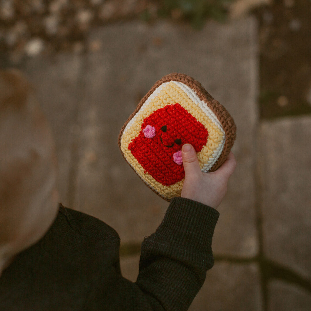 toddler holding slice of toast with jam plush toy rattle