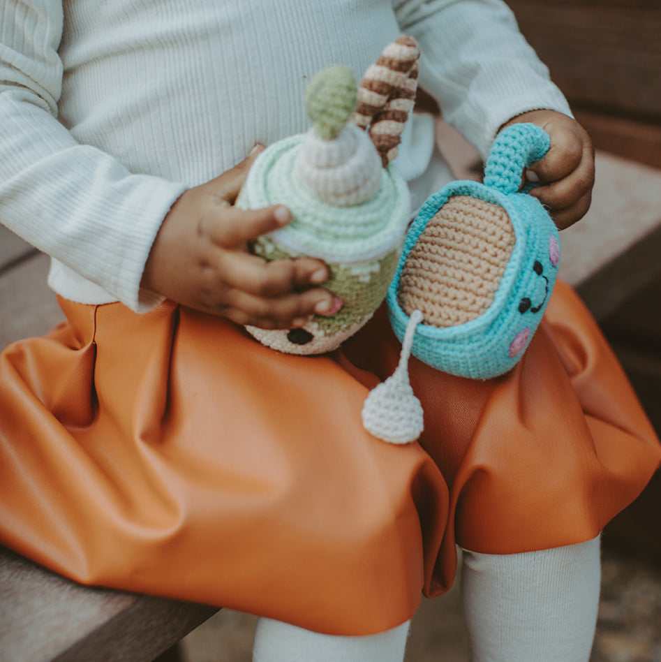 girl holding chai latte and green tea latte baby rattles