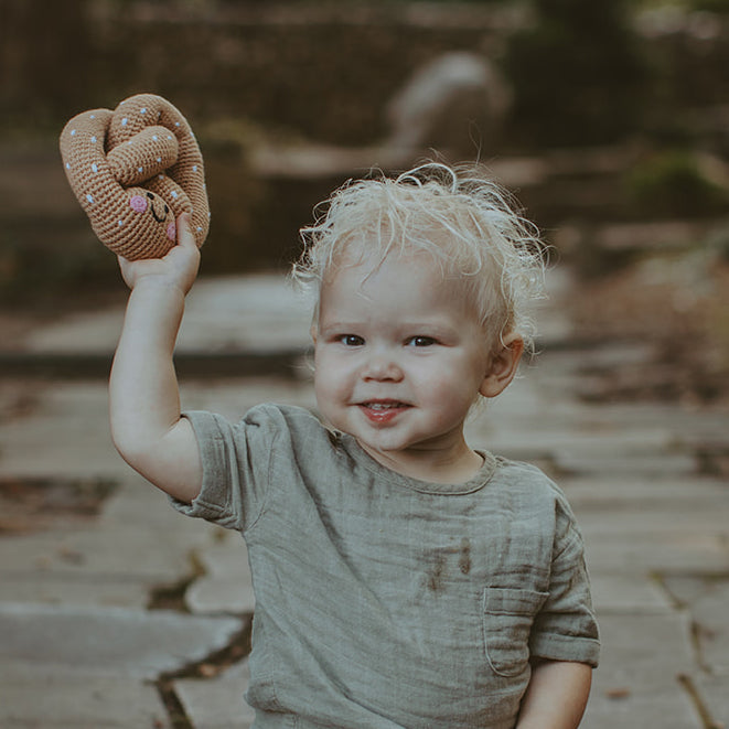 child holding up soft pretzel plush toy made with organic cotton yarn