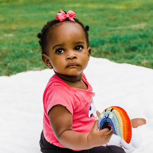 Baby holding bright rainbow crochet baby rattle