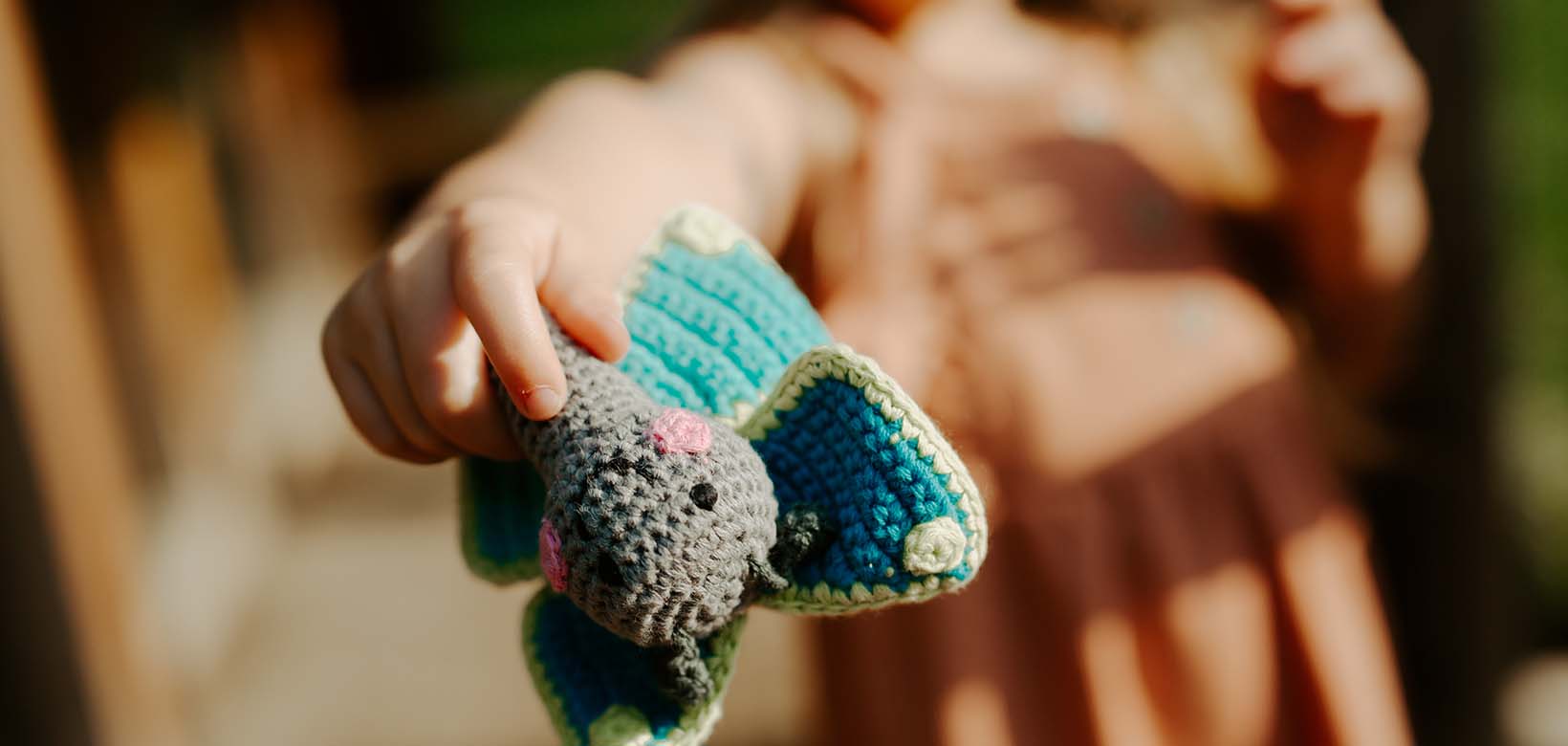 Child's hand holding Crochet Knit Baby Rattle Butterfly