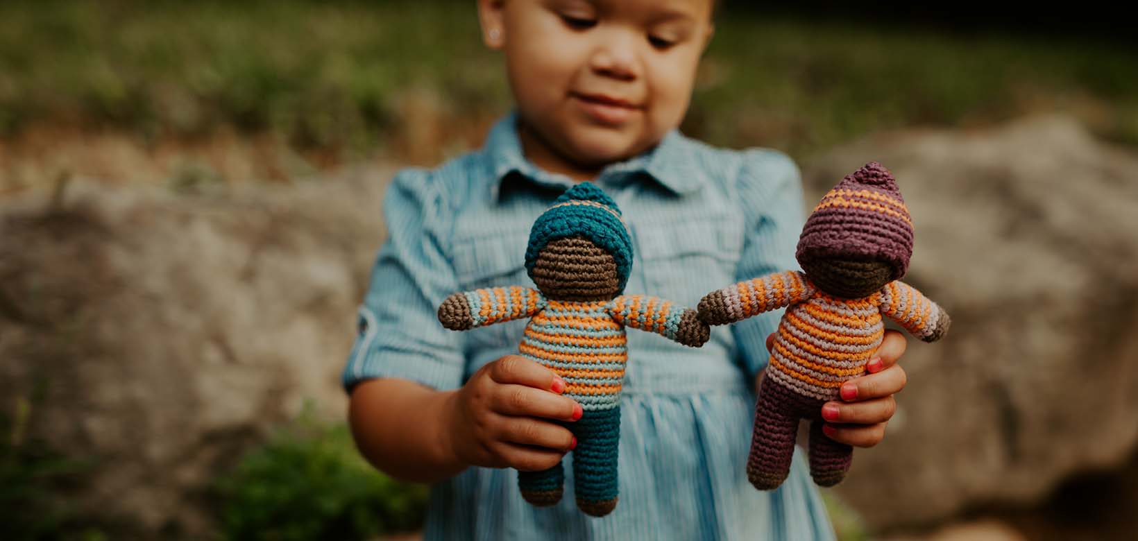 Girl holding Pixie Knitted Doll Toy Rattles.