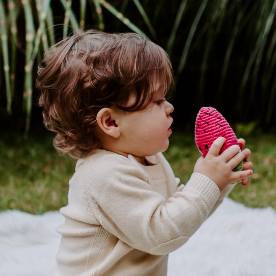 Toddler holding crochet pink watermelon baby toy