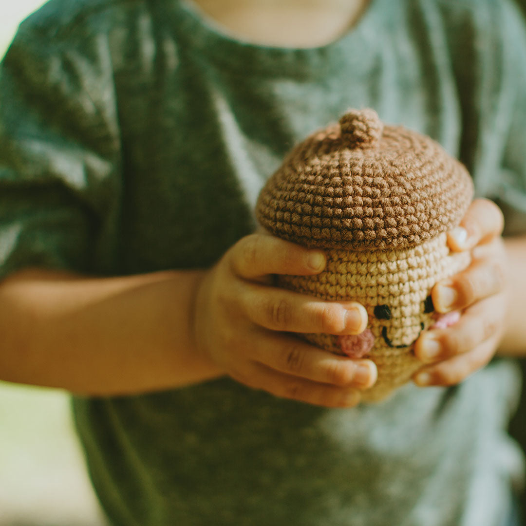 Toddler holding Brown Crochet Acorn Baby Toy Rattle