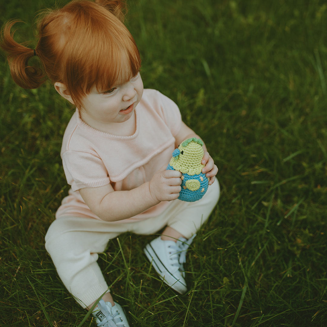 Girl playing with organic cotton yellow and blue baby chick toy.