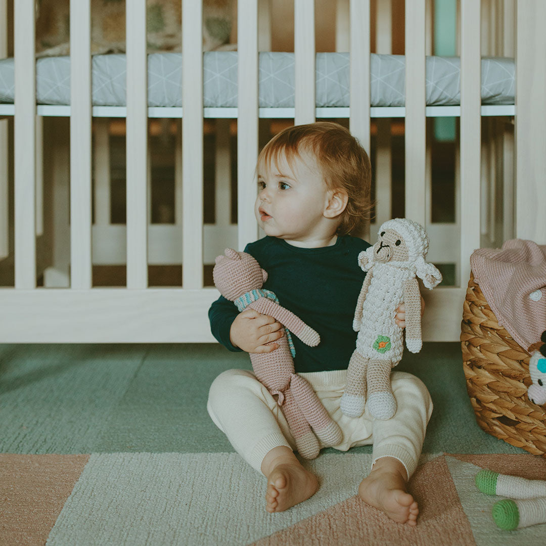 Toddler holding Crochet Organic Cotton Pig and Lamb Plush Toys