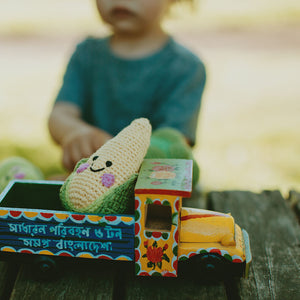 Toddler with plush crochet corn baby rattle on toy truck