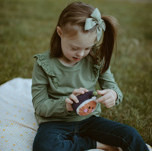girl holding fair trade crochet fig soft toy