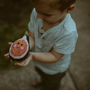 Boy holding crochet handmade fig baby rattle
